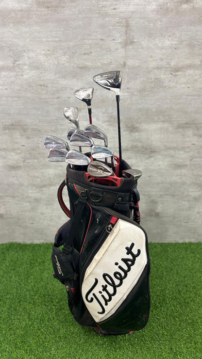 Titleist golf bag with golf clubs on a grassy surface and concrete wall background