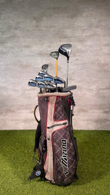 Golf clubs in a bag on a grassy surface with a gray wall background
