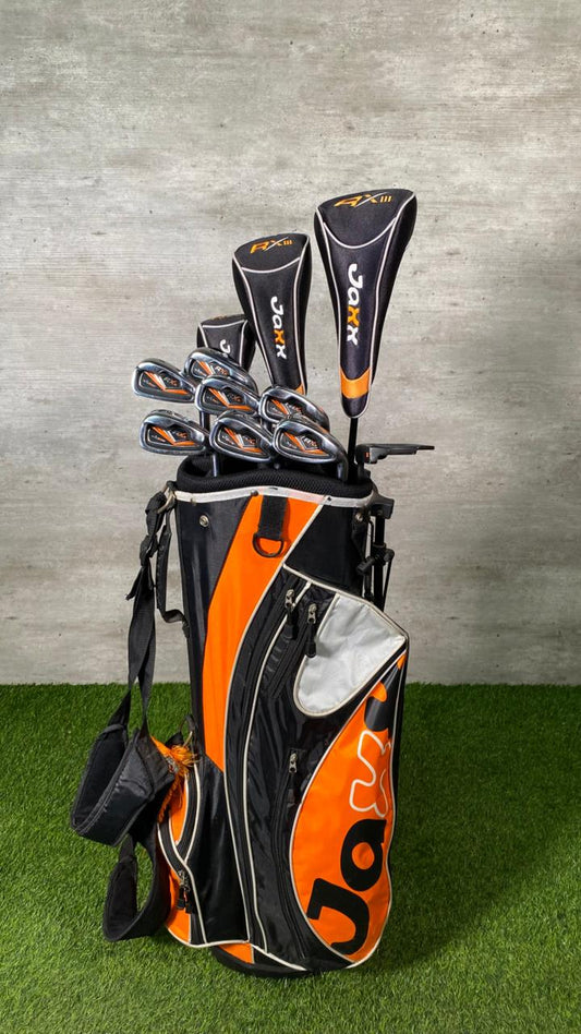 Golf bag with golf clubs on a grassy surface and concrete wall background