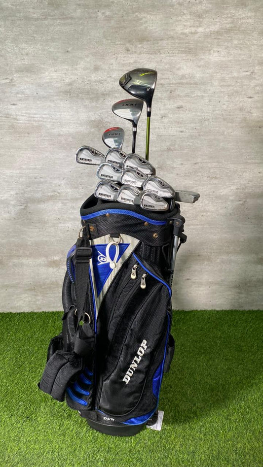 Golf clubs in a black and blue bag on a grassy surface with a gray wall background