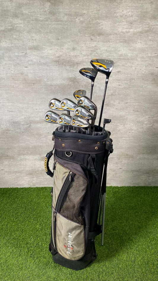 Golf club set in a bag on a grassy surface with a textured wall background