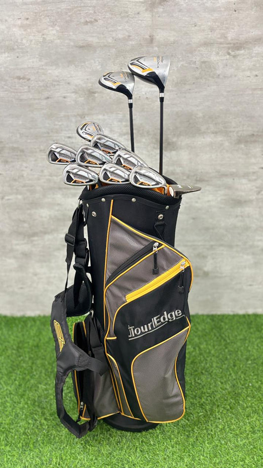 Golf clubs in a black and gray bag with yellow accents on a grassy surface.