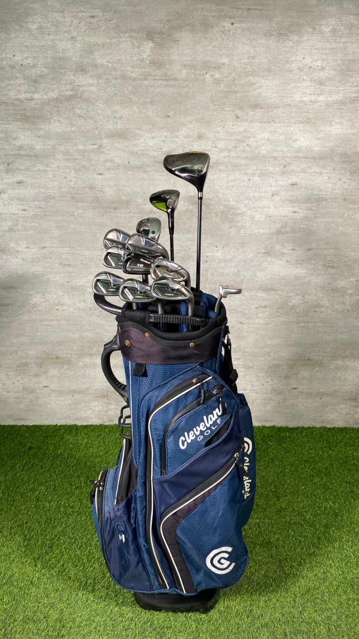 Blue golf bag with golf clubs against a gray wall