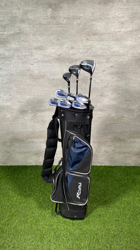 Set of golf clubs in a black and gray bag on green grass with a concrete wall background
