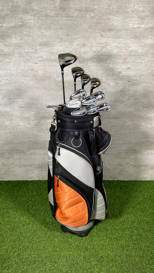 Golf bag with clubs on a grassy surface against a textured wall
