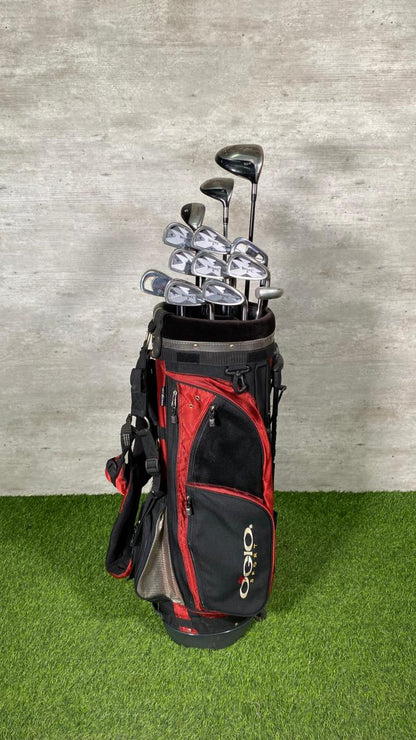 Golf clubs in a red and black bag on a green surface with a gray background
