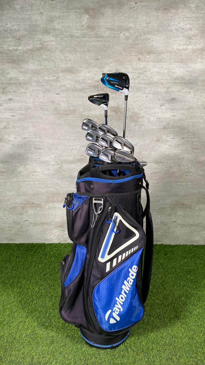 Golf bag with golf clubs on a grassy surface and concrete wall background