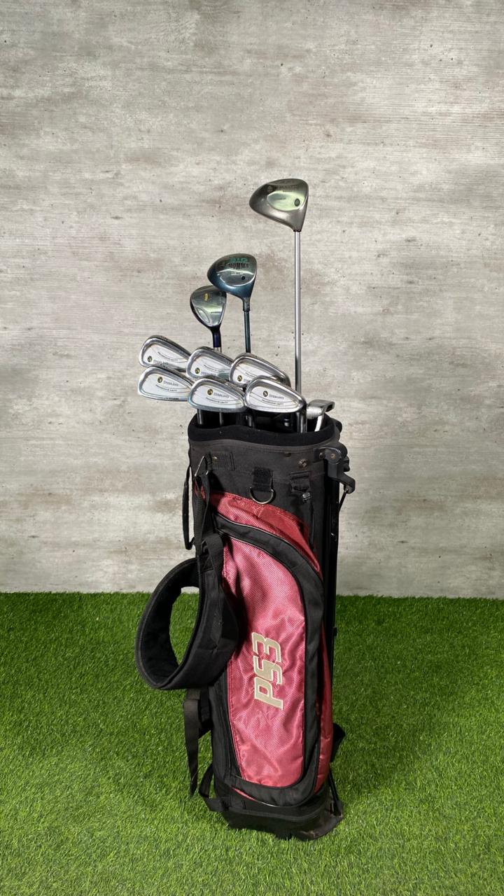 Golf club set in a black bag with pink interior on a grassy surface.
