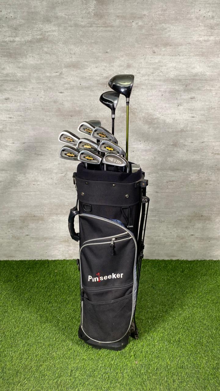 Golf clubs in a black bag on a green grass and gray concrete background