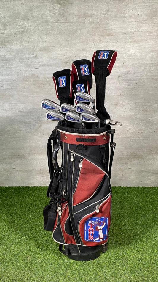Red and black golf bag with golf clubs on a grassy surface.