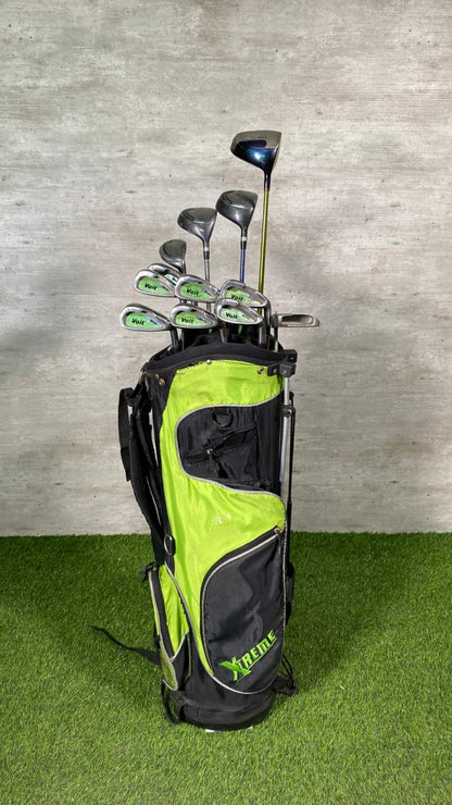 Golf clubs in a lime green and black bag on a grassy surface with a concrete wall background