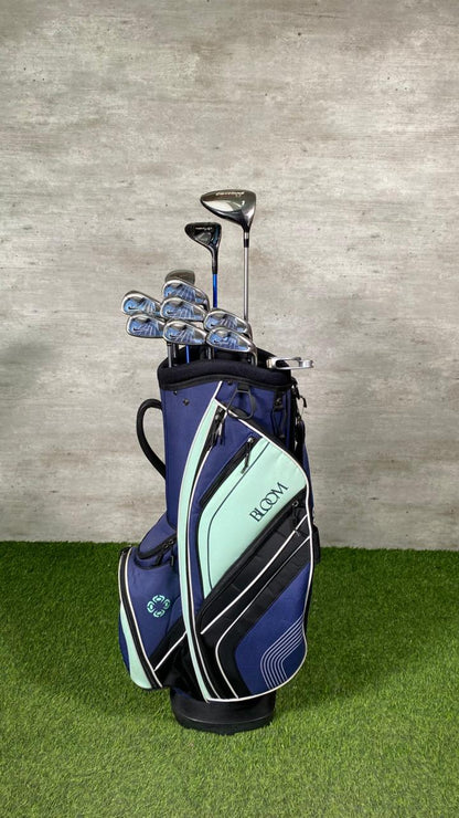Golf bag with clubs on a grassy surface against a concrete wall