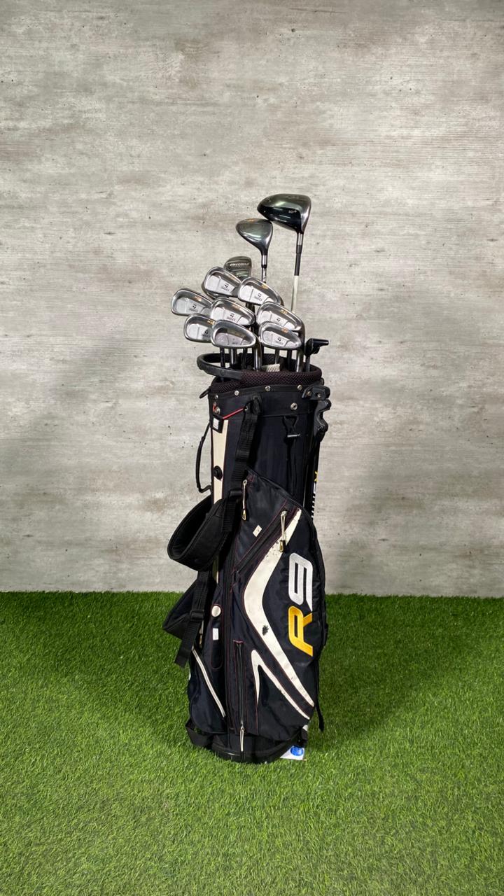Golf clubs in a black bag on a green grass and gray concrete background