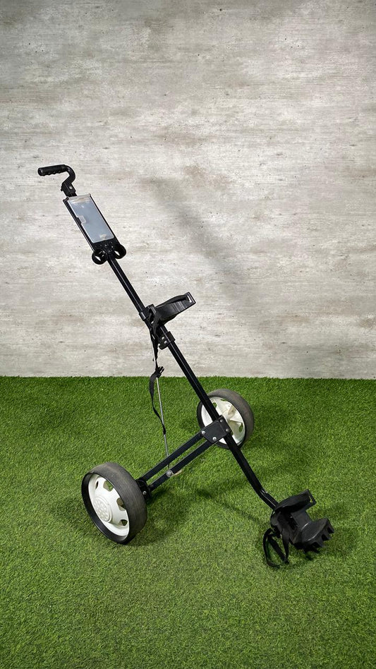 Golf push cart on a green surface with a gray wall background