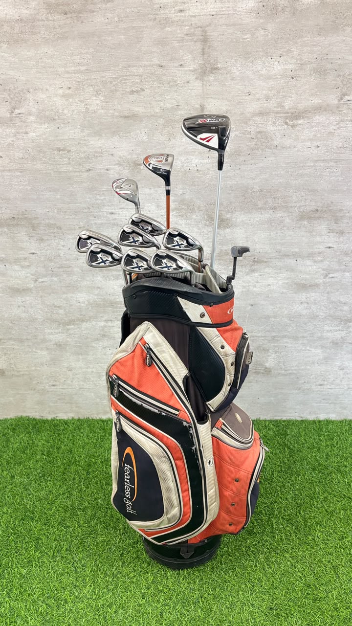 Golf clubs in an orange and black bag on a green and gray background