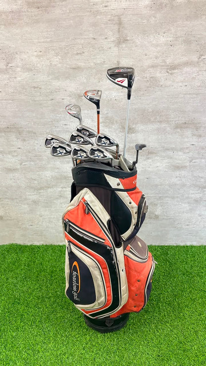 Golf clubs in an orange and black bag on a green and gray background