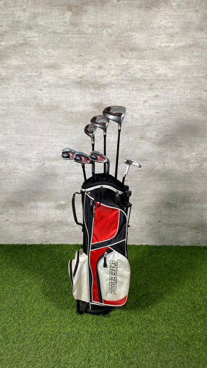 Golf clubs in a bag on grass with a gray wall background