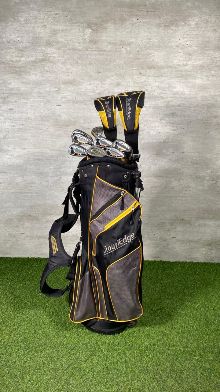 Golf bag with clubs on a grassy surface and concrete wall background