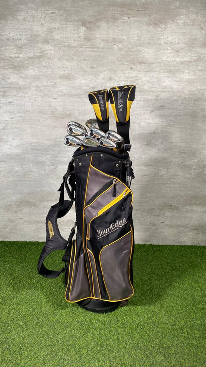 Golf bag with clubs on a grassy surface and concrete wall background