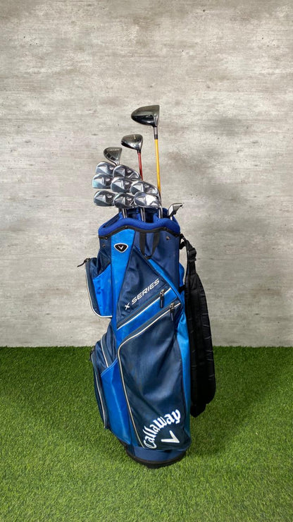 Blue Callaway golf bag with golf clubs against a gray wall.