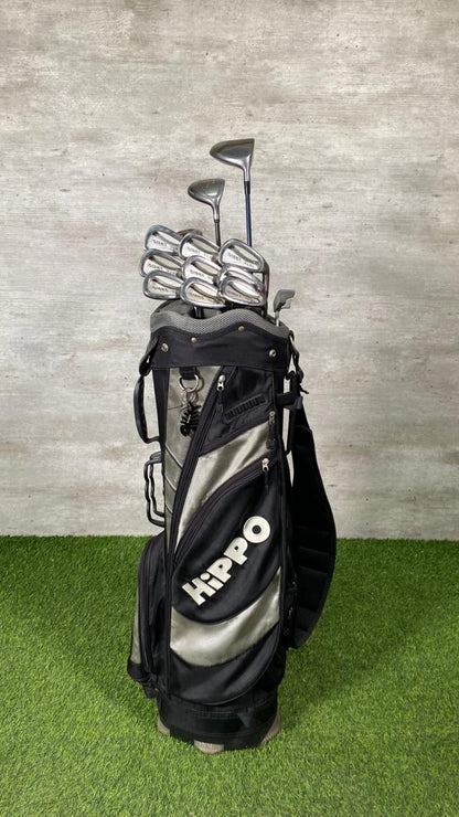 Golf bag with clubs on a grassy surface against a textured wall