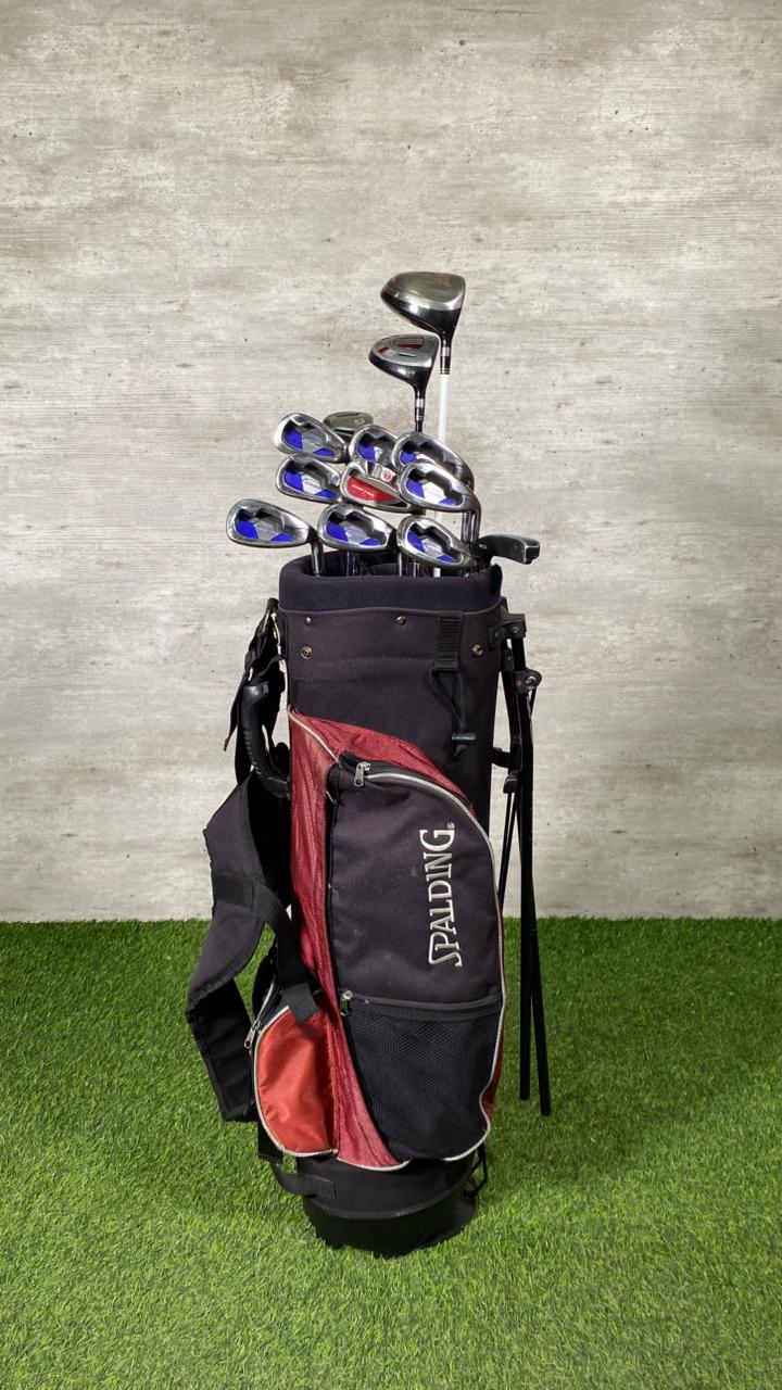 Golf bag with golf clubs on a grassy surface with a gray wall background