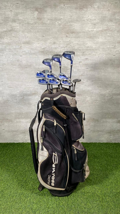 Golf clubs in a bag on a grassy surface with a gray concrete wall background