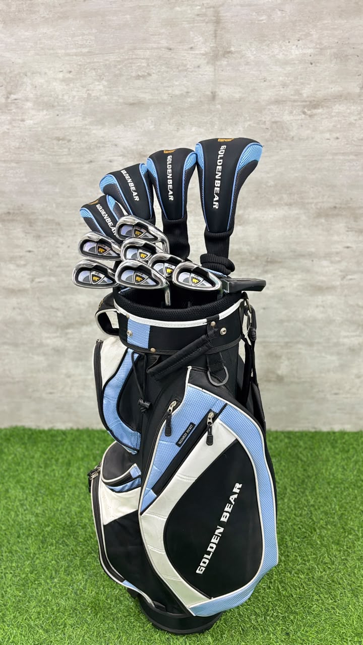 Golf club set with blue and black clubs in a black and blue bag on grass.