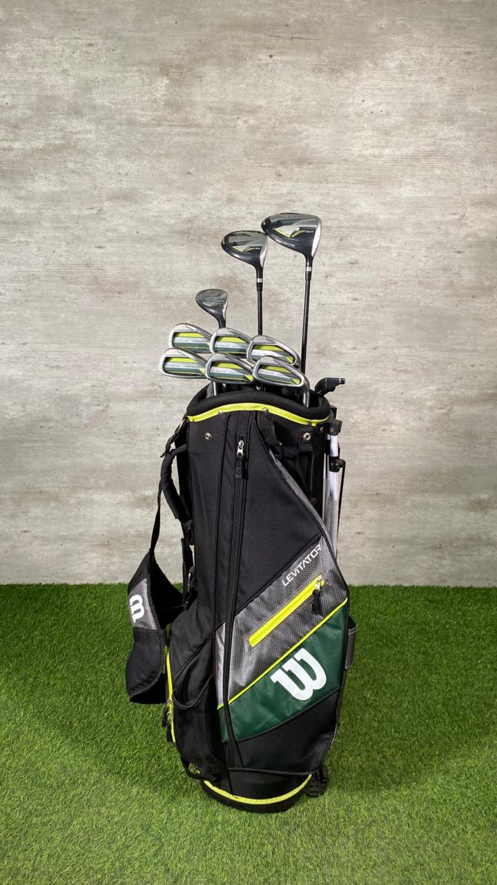 Golf bag with golf clubs against a gray wall