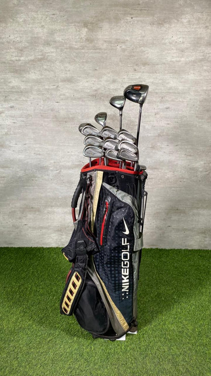 Golf clubs in a Nike golf bag on grass with a concrete wall background