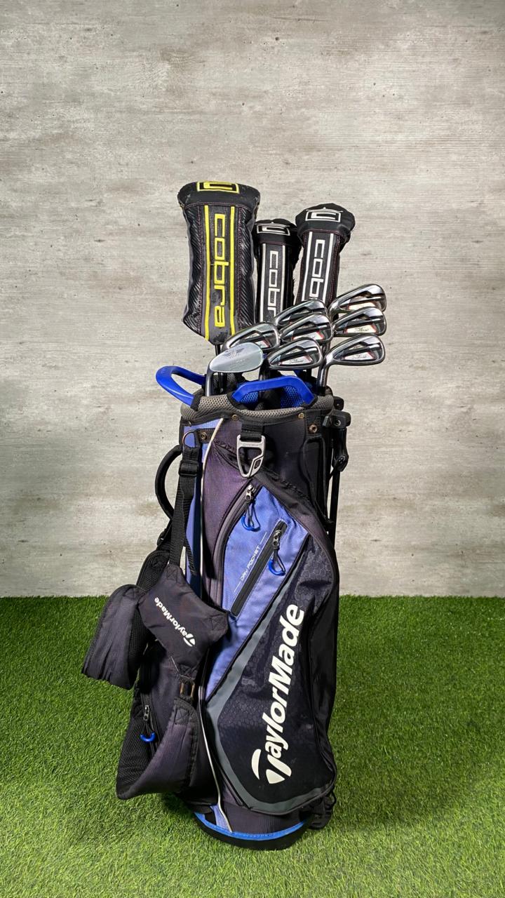Golf clubs in a TaylorMade bag on a grass and concrete background