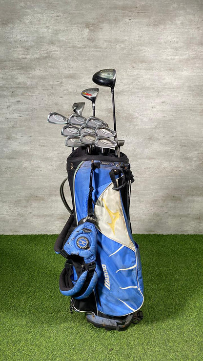 Golf clubs in a blue bag on a green surface with a gray concrete wall background