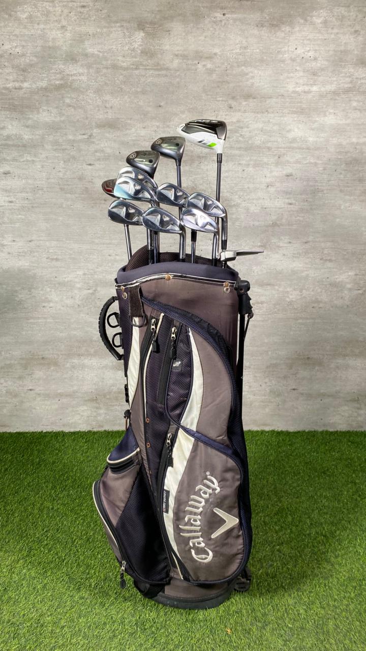 Callaway golf bag with golf clubs on a grassy surface and concrete wall background