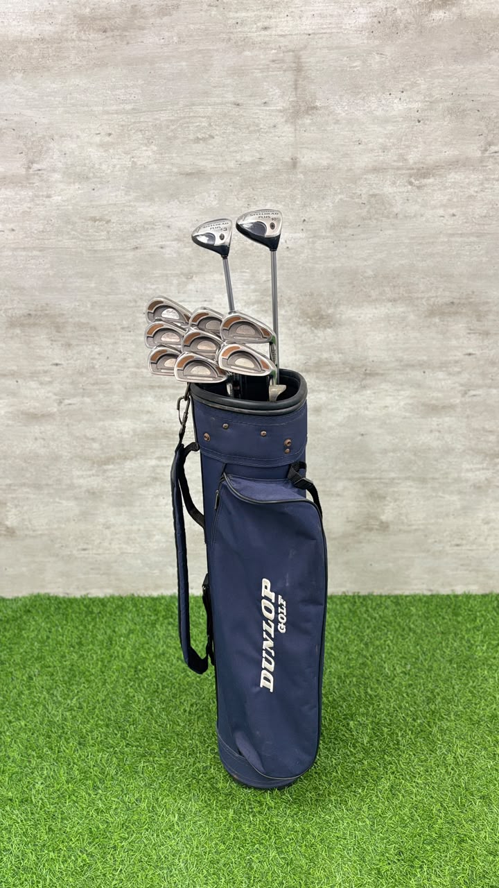 Set of golf clubs in a navy blue bag on a green and gray background