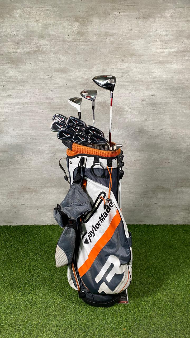 Golf clubs in a bag on grass with a concrete wall background