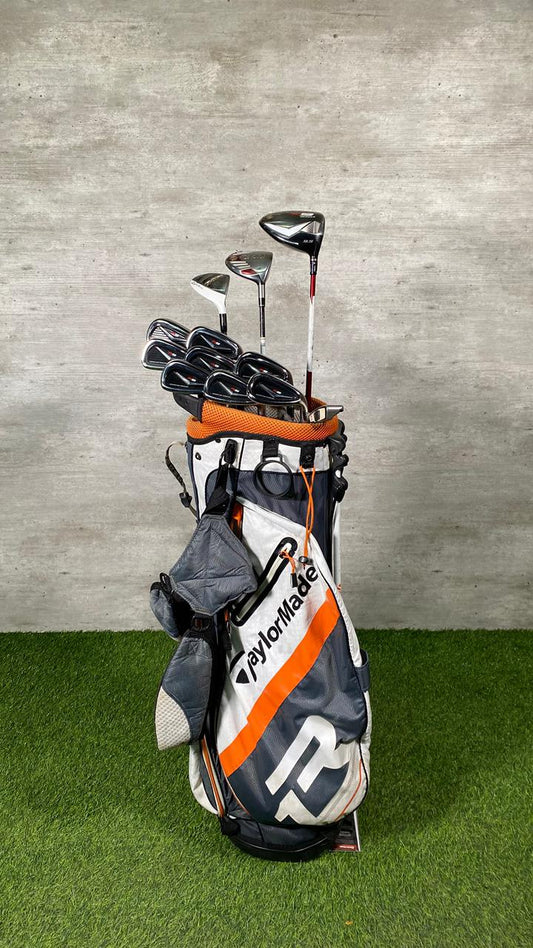 Golf clubs in a bag on grass with a concrete wall background