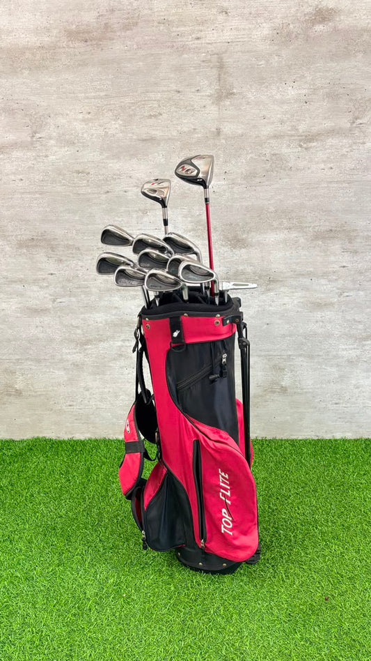 Red golf bag with golf clubs on a grassy surface and concrete wall background