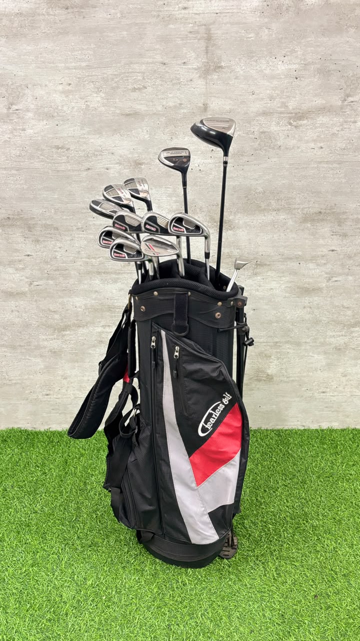 Golf bag with golf clubs on a grassy surface with a concrete wall background