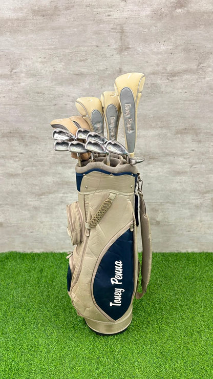 Golf club set in a beige bag with navy blue logo on grass and concrete background