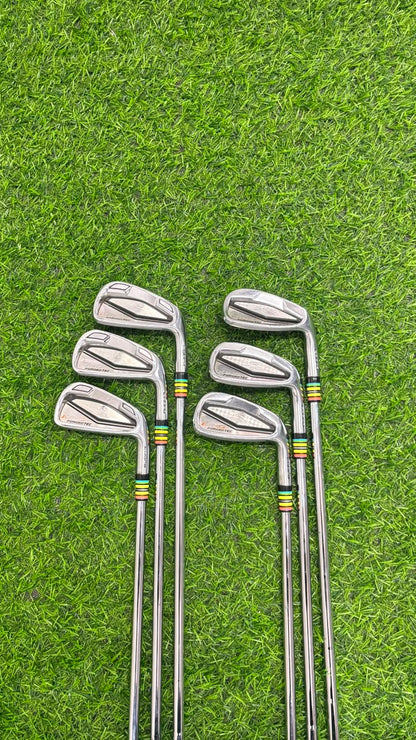 A set of eight golf iron clubs arranged in two vertical rows on a green grass surface.