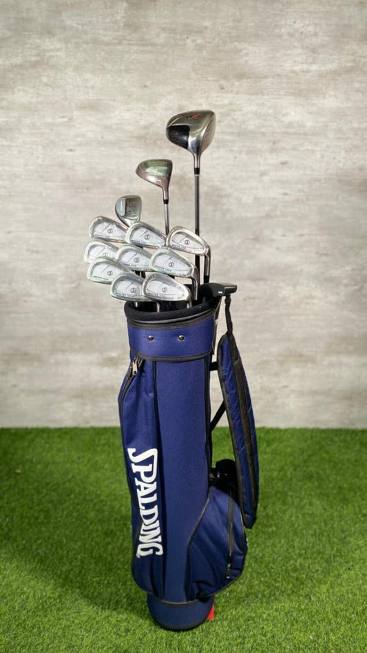Spalding golf bag with golf clubs on a green surface and gray wall background