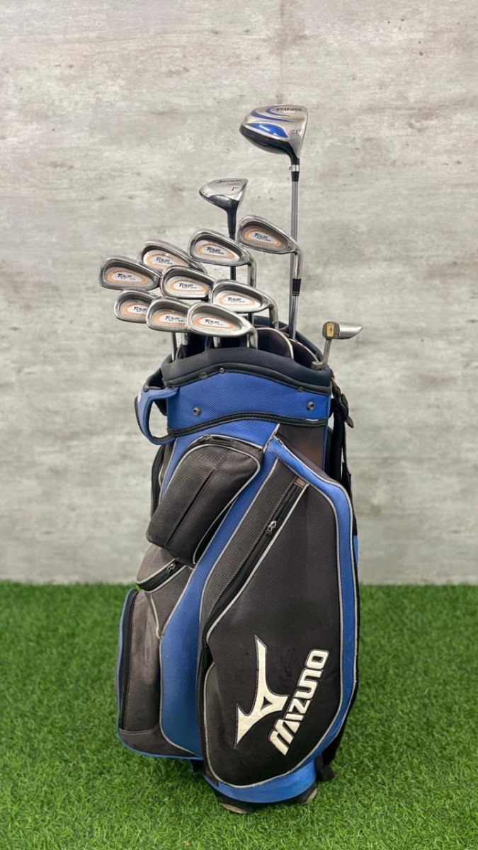 Golf club set with Mizuno bag on grass against a concrete wall