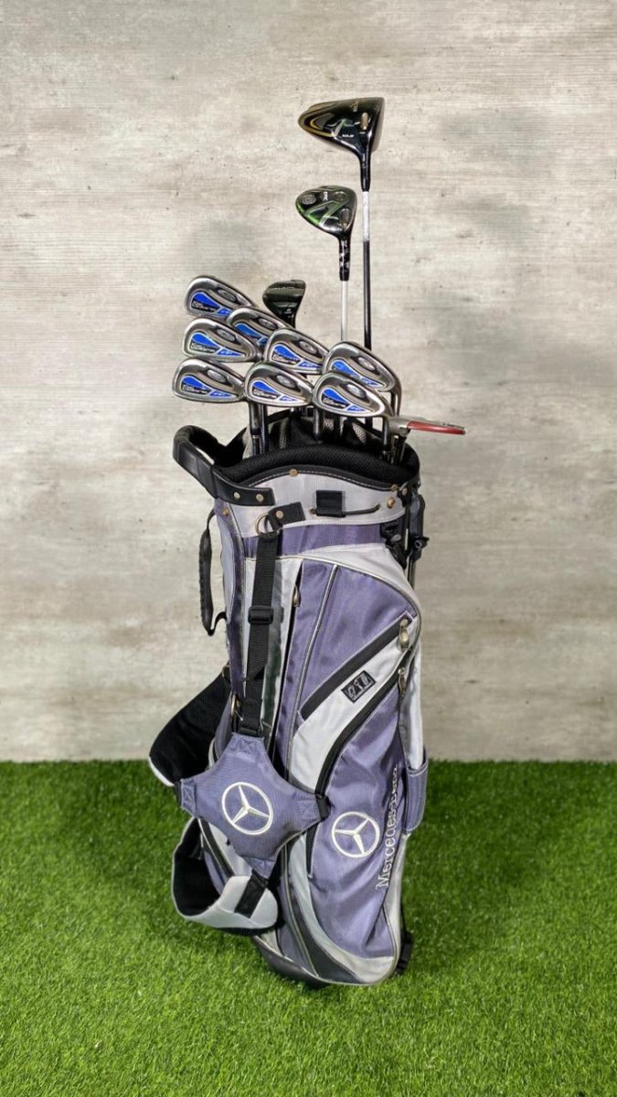 Golf bag with clubs on a green surface and gray wall background