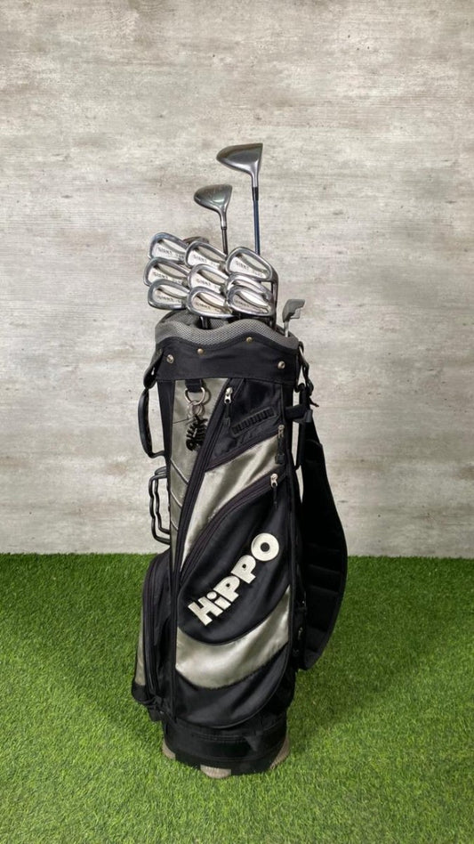 Golf bag with clubs on a grassy surface against a textured wall