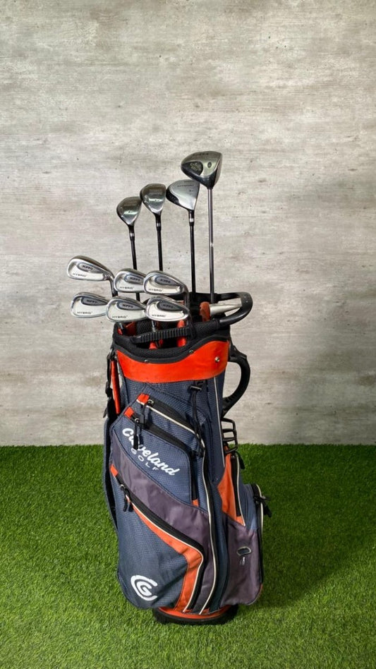 Golf clubs in a Callaway bag on grass with a concrete wall background