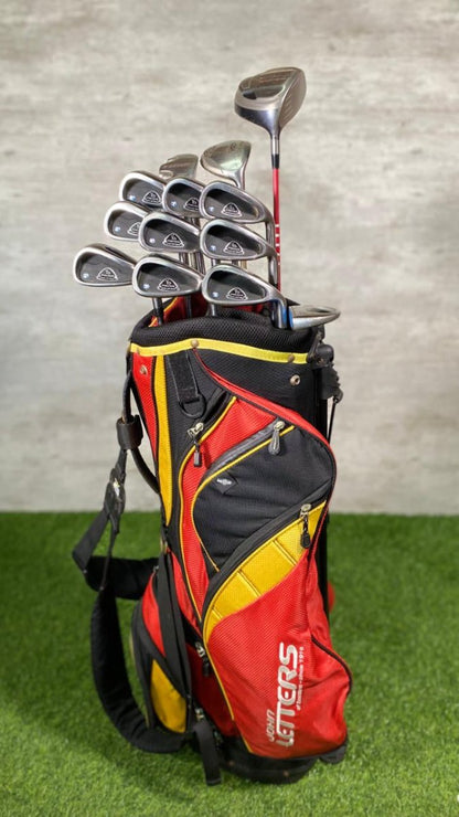 Red and black golf bag with golf clubs on a grassy surface