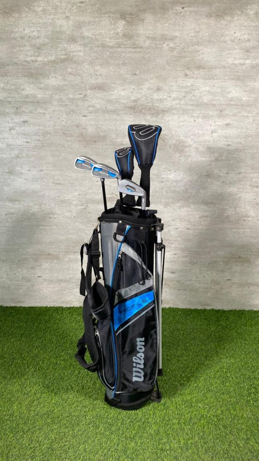 Golf bag with clubs on a green surface and gray wall background