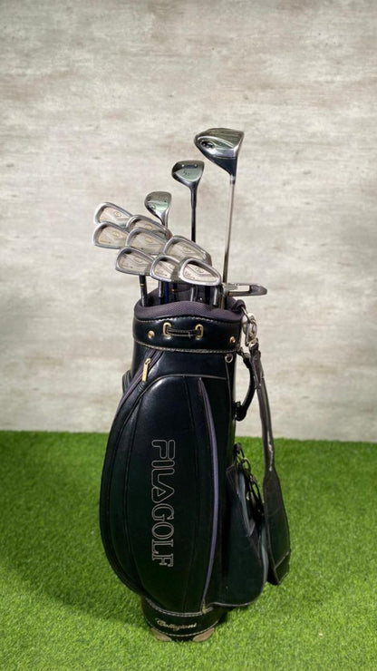 Golf club set in a black FILA GOLF bag on green grass with a gray wall background