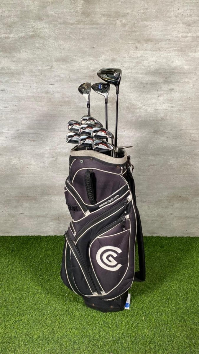 Golf bag with clubs against a gray wall on green grass