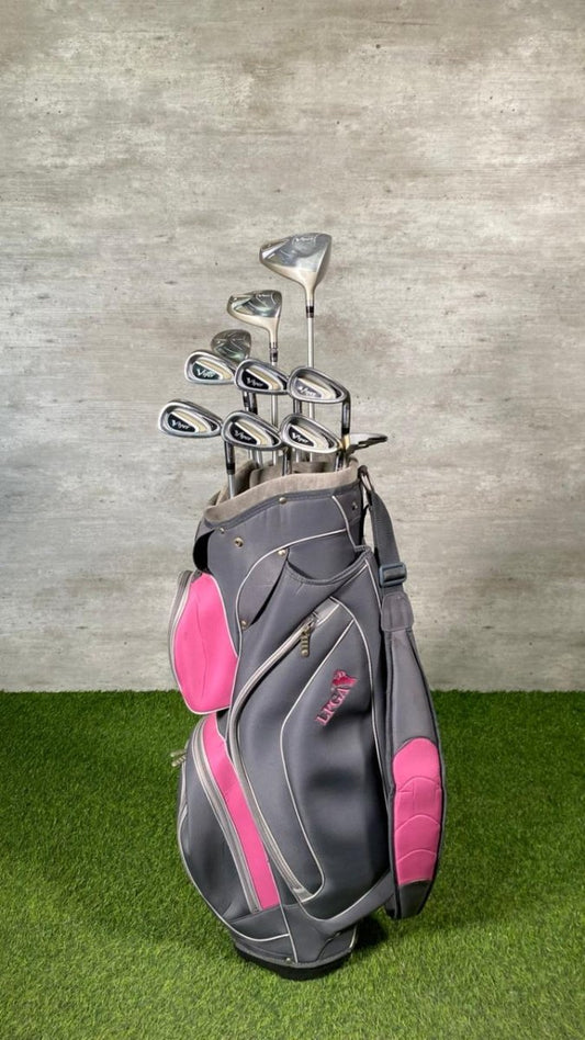 Gray and pink golf bag with golf clubs on a grassy surface and concrete wall background
